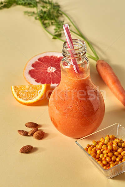 Citrus vegetable smoothies with berries and nuts in a glass on an orange paper background Stock photo © artjazz