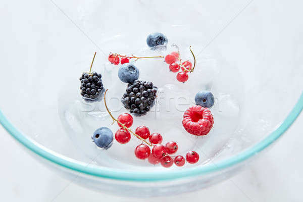 Close-up blackberries, blueberries,raspberries, currants and ice cubes in a glass transparent bowl o Stock photo © artjazz