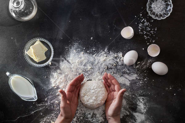 Woman's hands knead dough on table with flour Stock photo © artjazz