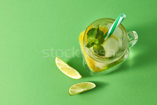 Refreshing homemade sparkling lemonade with ice in mason jar, slices of lime and lemon, leaf of mint Stock photo © artjazz