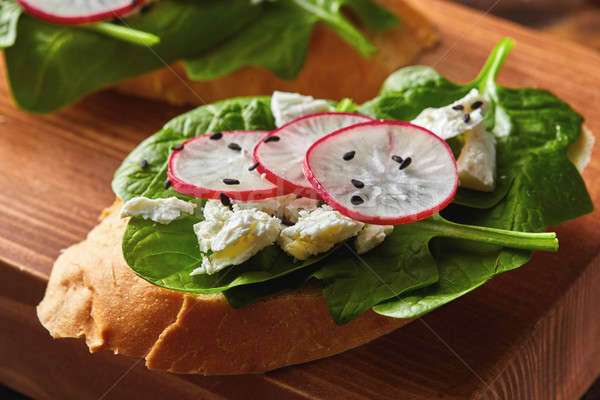 Light healthy sandwiches with bread toasts, soft cheese and freshly gathered organic radishes, spina Stock photo © artjazz