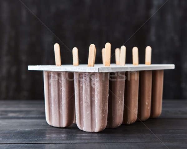 Plastic molds with coffee ice cream on a stick presented on a dark wooden background with copy space Stock photo © artjazz