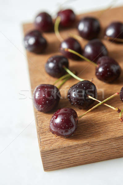 Close-up ripe sweet cherry in water droplets on a wooden board on white background with soft focus. Stock photo © artjazz