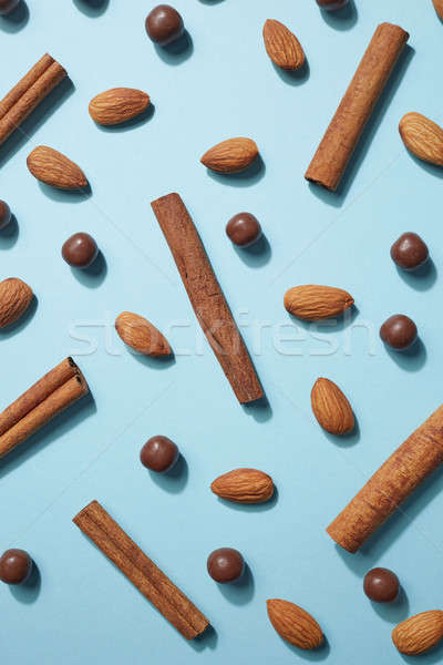 Fresh almonds, chocolate balls and cinnamon on a blue paper background, creative pattern. Flat lay Stock photo © artjazz