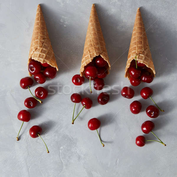 Pattern of freshly picked ripe cherries in a sweet wafer cones on a gray concrete table. Cherry on a Stock photo © artjazz