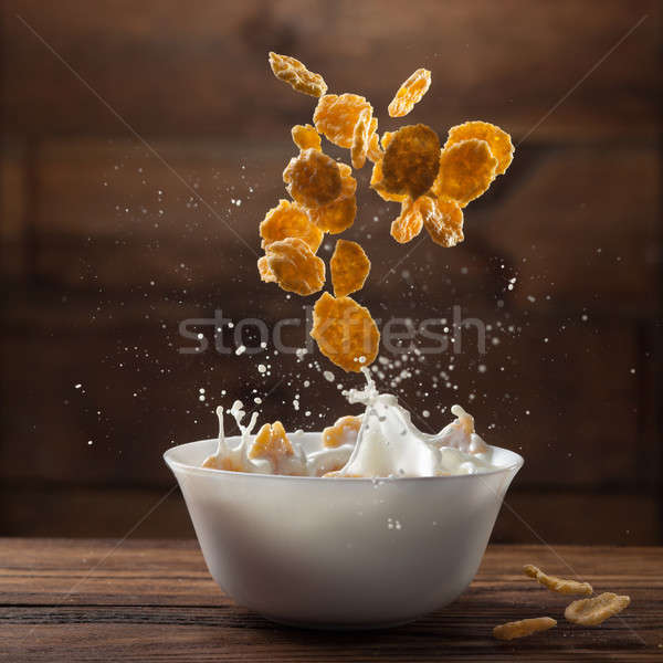 Falling corn flakes with milk splash on wood Stock photo © artjazz