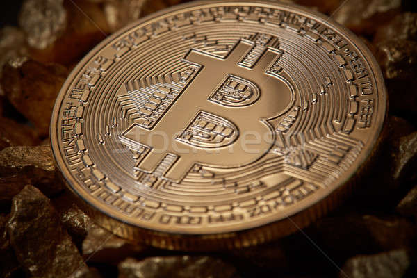 Close up golden bitcoin token on mound of gold nuggets. Cryptocurrency concept. Stock photo © artjazz
