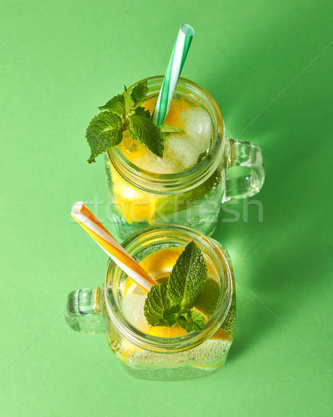 Citrus fruits slices of lemon and lime, ice, water and plastic straws in the glass on a green backgr Stock photo © artjazz