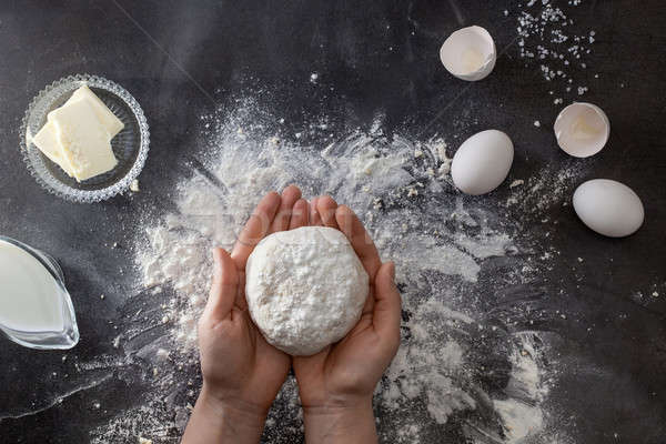 Woman's hands knead dough on table with flour Stock photo © artjazz