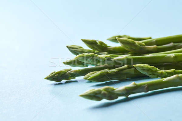 Healthy organic green asparagus stalks ready to cook on blue background Stock photo © artjazz