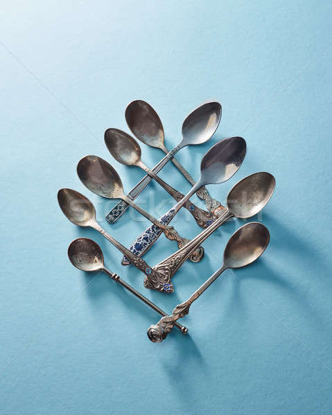 Cutlery set of silver tablespoon dessert spoon and tea spoon isolated on blue Stock photo © artjazz