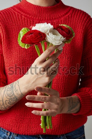 Stylish girl in a red sweater holding a bouquet of different flowers Ranunculus on a gray background Stock photo © artjazz