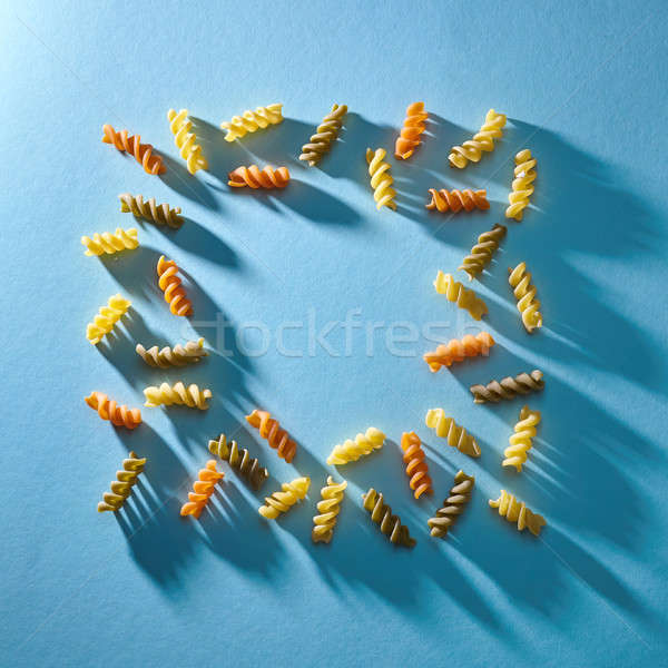 Frame in the shape of a square of multicolored pasta on a blue background. Flat lay. Stock photo © artjazz
