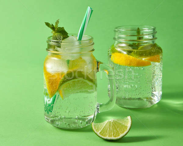 Two glass jar with a cold natural homemade lemonade with bubbles of air. Citrus fruits slices, ice,  Stock photo © artjazz