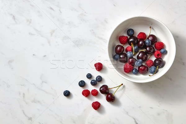 Organic fresh blueberry, cherry, raspberry in a ceramic dish on a gray stone background with place f Stock photo © artjazz