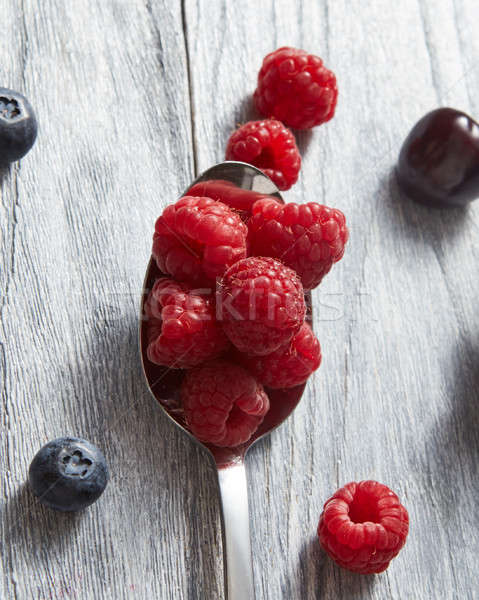 Big spoon with ripe red fresh raspberry on gray background. Stock photo © artjazz