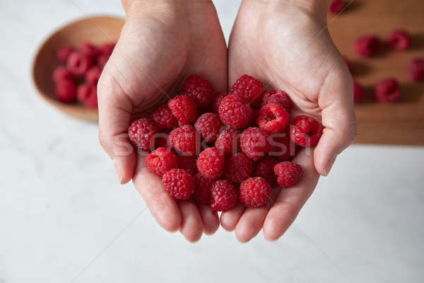 Home grown natural fresh red raspberry for cooking jam in a woman hands above a white kitchen table. Stock photo © artjazz