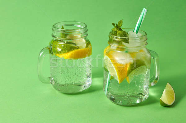 Summer refreshing drink on a green background. Homemade sparkling cocktail in glass jars. Concept of Stock photo © artjazz