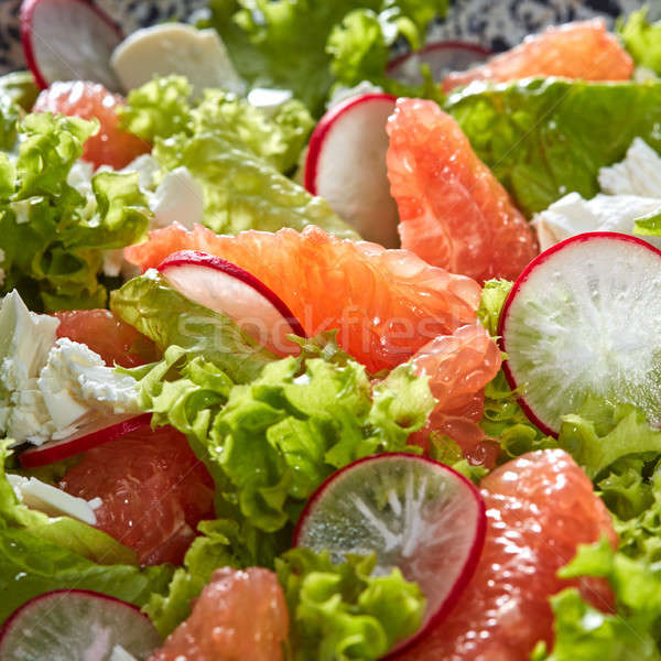 Natural fresh salad from lettuce, grapefruit, slices of radish and cheese. Close-up view from above. Stock photo © artjazz