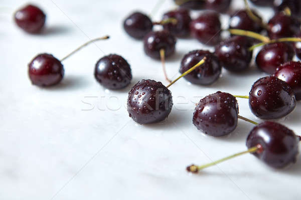 Red sweet cherries in water drops on a marble background with copy space. Stock photo © artjazz