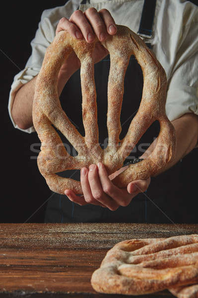 Baker's hands hold fougas bread Stock photo © artjazz