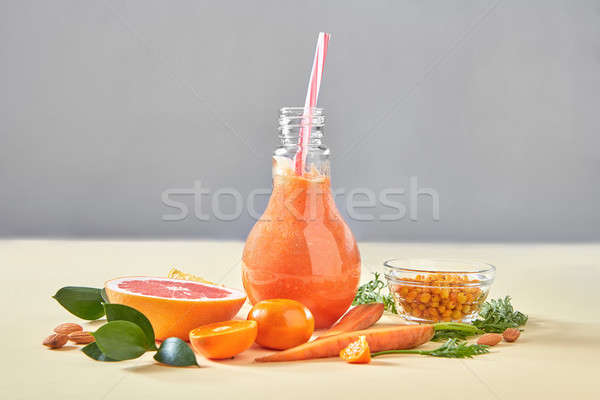Homemade orange smoothies with carrot, grapefruits, sea buckthorn, almonds in glass bottle on a yell Stock photo © artjazz