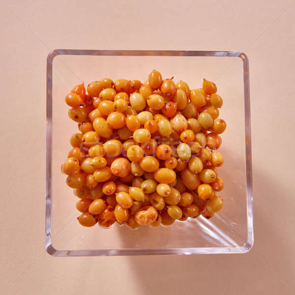 Natural organic sea buckthorn in the glass plate - yellow ripe sweet berries on a beige paper backgr Stock photo © artjazz
