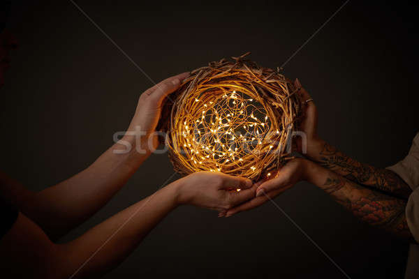 Hands of a man and a woman holding a wreath of branches with yellow Christmas lights around a black  Stock photo © artjazz