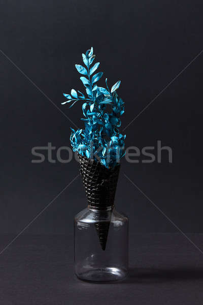 A black wafer cone with branch of blue painted leaf in a glass j Stock photo © artjazz