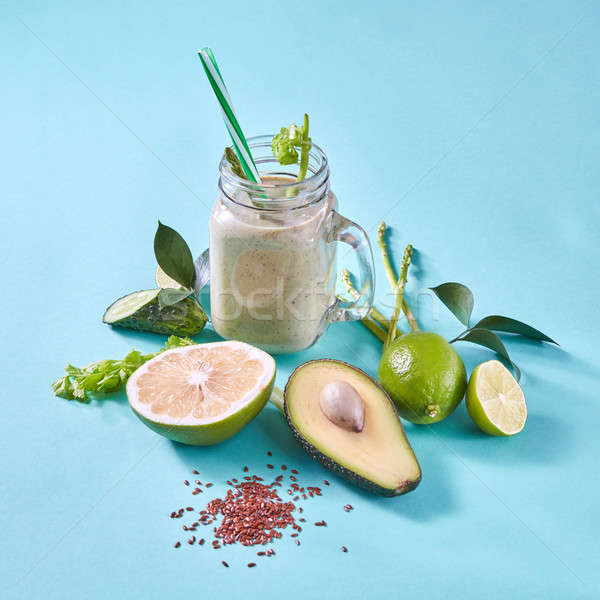 Homemade green smoothies with slices lemon, lime, avocado, selery, cucumber with flax seeds on a blu Stock photo © artjazz