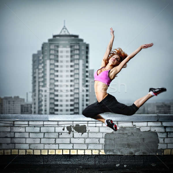 Stock photo: girl posing on the roof against city background