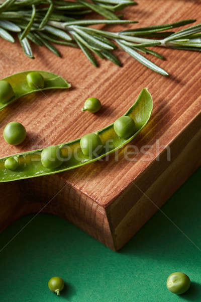 Opened sticks with green natural beans of peas and sprig of rosemary on a wooden cutting board on a  Stock photo © artjazz