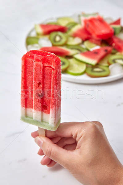 A woman's hand holds frozen berry smoothies against the background of a gray marble table with a pla Stock photo © artjazz