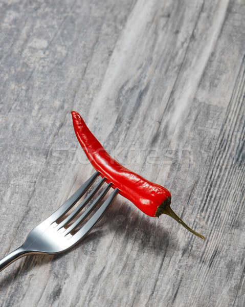 Red hot chilli on a metal fork on wooden background Stock photo © artjazz