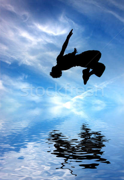 silhouette of jumping man against blue sky and clouds Stock photo © artjazz