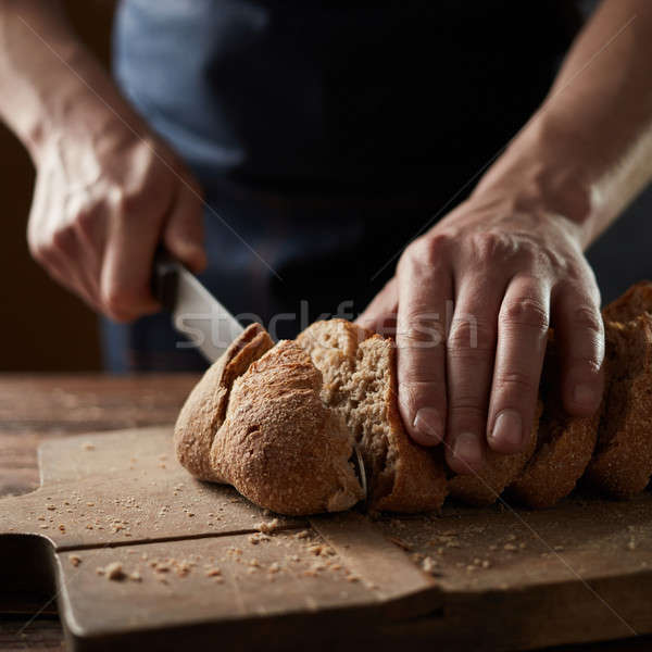 Male hands cutting wheaten bread, closeup Stock photo © artjazz