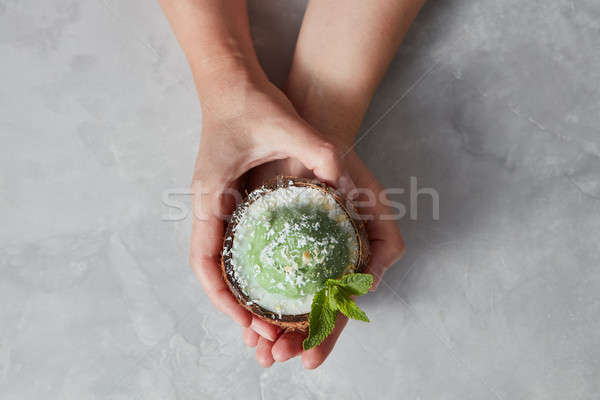 Womans hands take a halh of coconur with tasty homemade green ic Stock photo © artjazz