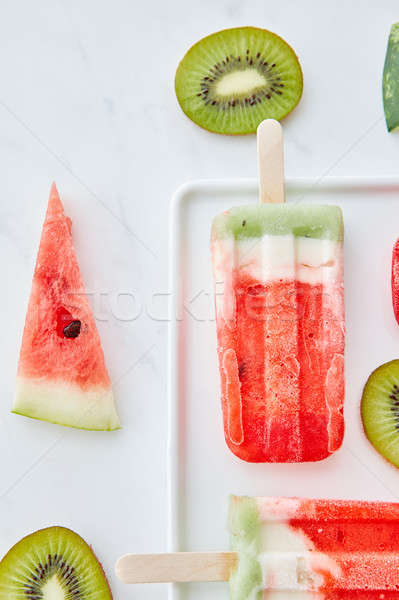 Appetizing composition of ice lolly on a stick and juicy pieces of watermelon and kiwi on a gray mar Stock photo © artjazz
