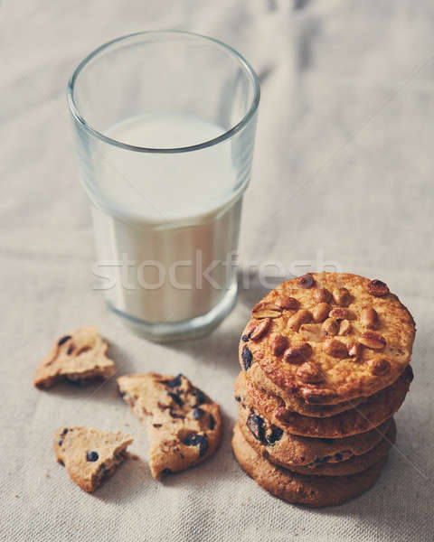 The glass of milk with a stack of cookies with chocolate chunks and peanut on a textile towel backgr Stock photo © artjazz