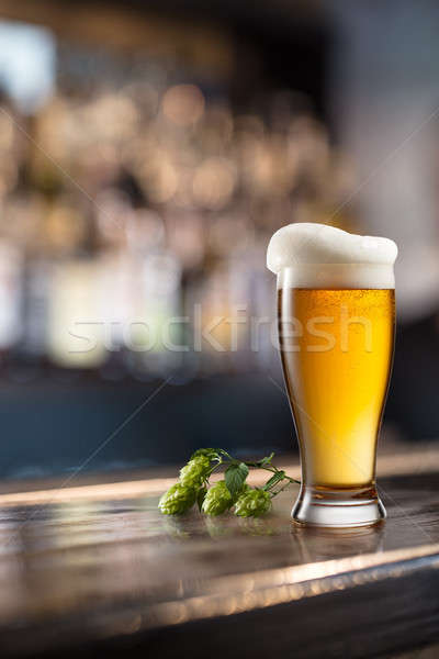 Glass of beer on wooden table and blurred background. Stock photo © artjazz