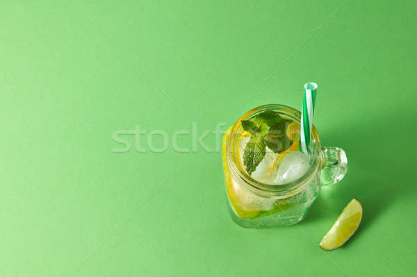 Homemade sparkling cold alcoholic mojito from natural citrus fruits with plastic straws on a green b Stock photo © artjazz