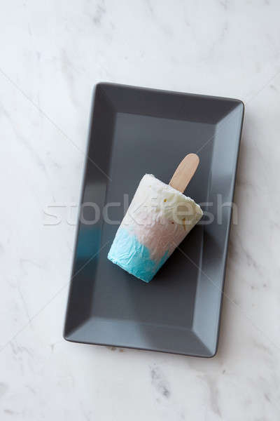 Colored appetizing ice cream on a stick in a black plate on a gray marble background with copy space Stock photo © artjazz