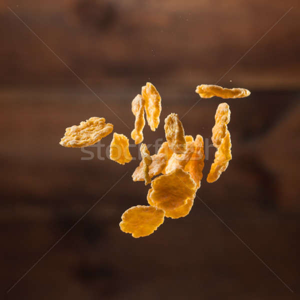 Falling corn flakes on wooden background Stock photo © artjazz