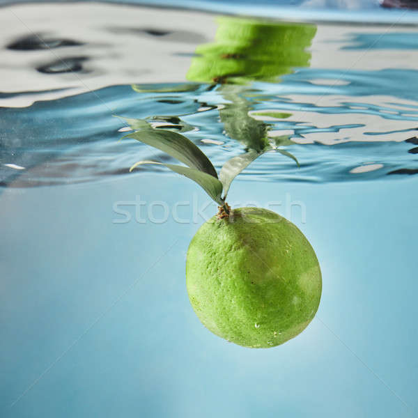 Fresh lime dropped into water with splash isolated on blue Stock photo © artjazz