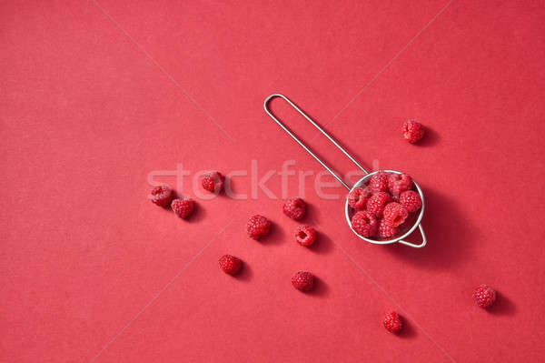 Freshly picked sweet raspberry on a red paper background. Colorful organic berries pattern. Stock photo © artjazz