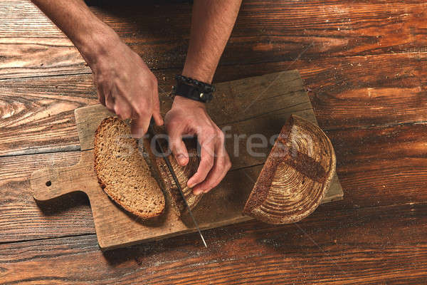 Men's hands cut fresh bread Stock photo © artjazz