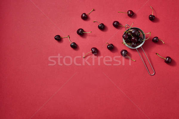 Freshly picked sweet cherry on a red paper background. Colorful organic berries pattern. Stock photo © artjazz
