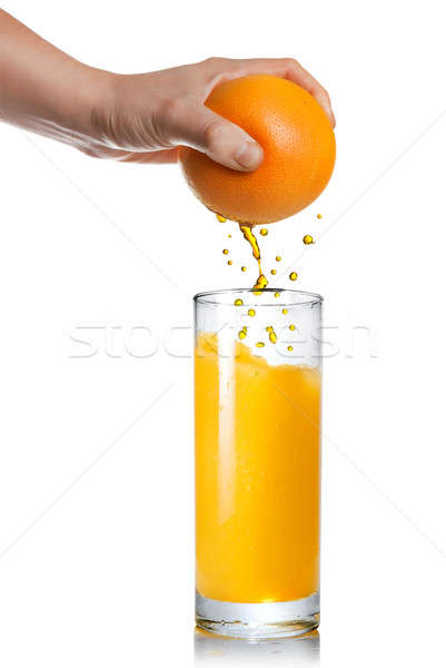Stock photo: squeezing orange juice pouring into glass isolated on white