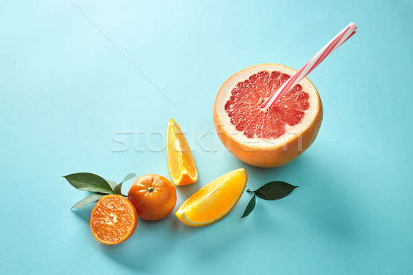 Orange and mandarin slice with halves grapefruit and red straw on blue background Stock photo © artjazz