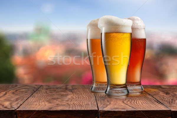 Glasses of different beer on wooden table against Prague Stock photo © artjazz